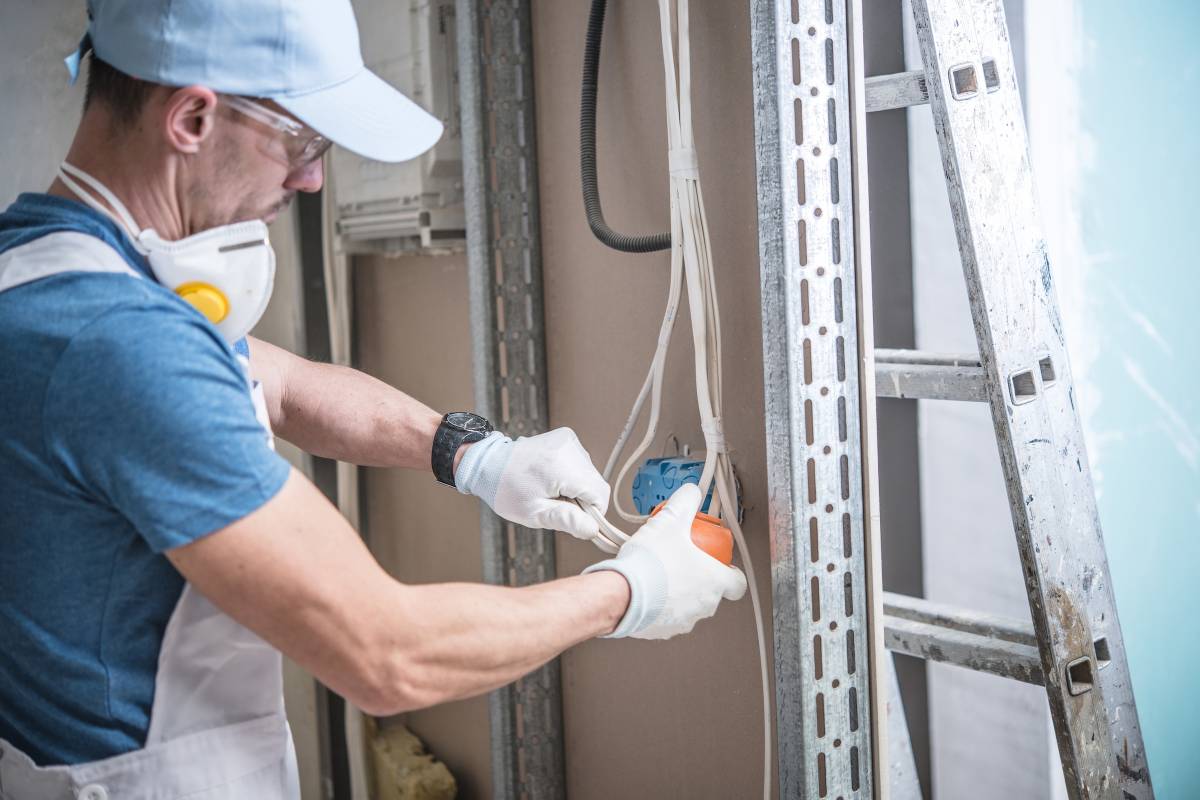 Electrical Installation Design. Caucasian Electrician Installing Electric Outlet in the Residential Construction.